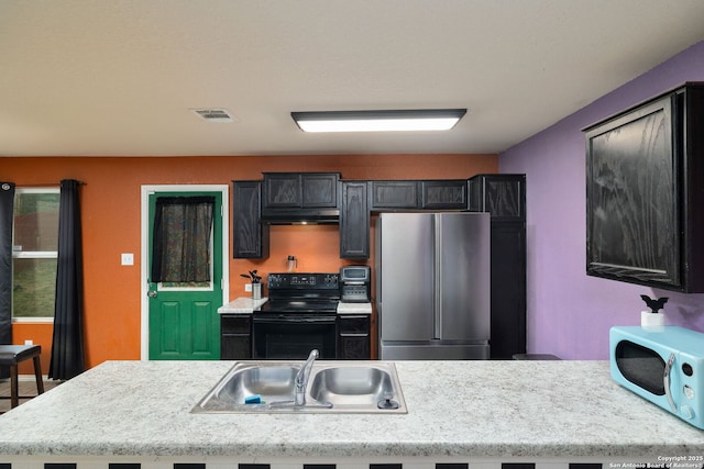 kitchen with black electric range oven, stainless steel fridge, and sink