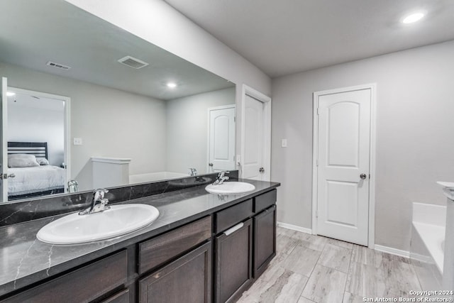 bathroom with vanity, wood-type flooring, and a bath