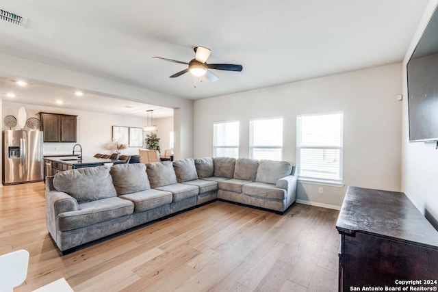 living room with ceiling fan, sink, and light hardwood / wood-style floors