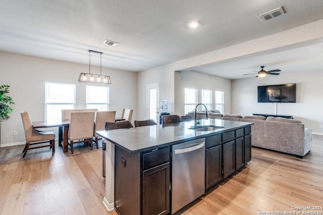 kitchen featuring pendant lighting, sink, a kitchen island with sink, stainless steel dishwasher, and light hardwood / wood-style flooring