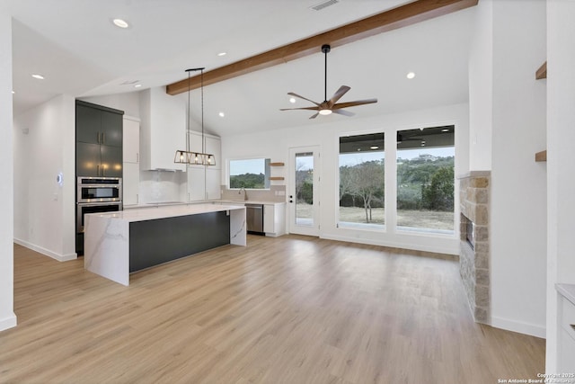 kitchen with dishwasher, hanging light fixtures, a large island, light hardwood / wood-style floors, and beam ceiling