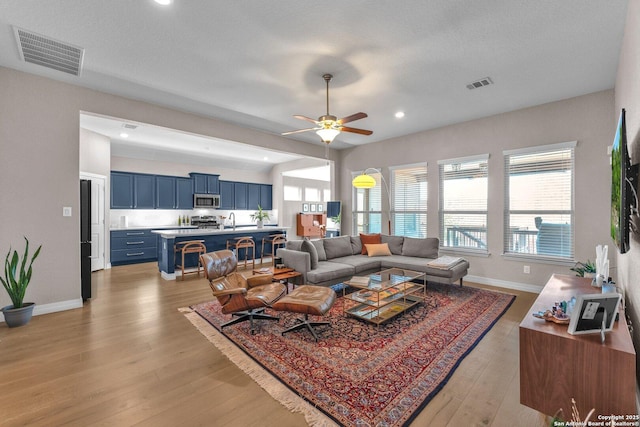 living room featuring sink, ceiling fan, and light hardwood / wood-style flooring