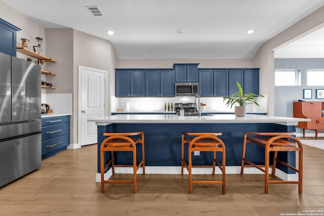 kitchen featuring light wood-type flooring, a kitchen island, blue cabinetry, and appliances with stainless steel finishes