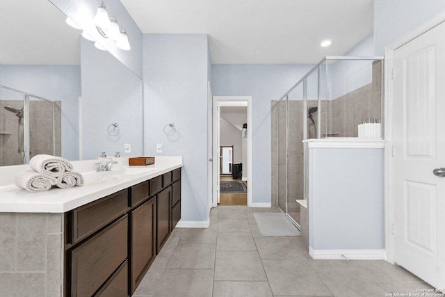 bathroom with a shower with door, vanity, and tile patterned floors