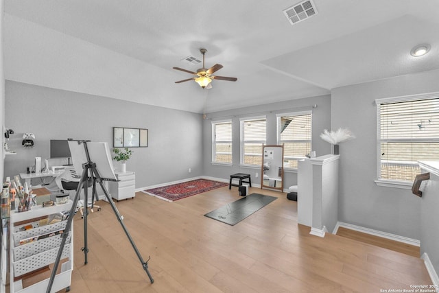 workout area with ceiling fan, lofted ceiling, and light wood-type flooring