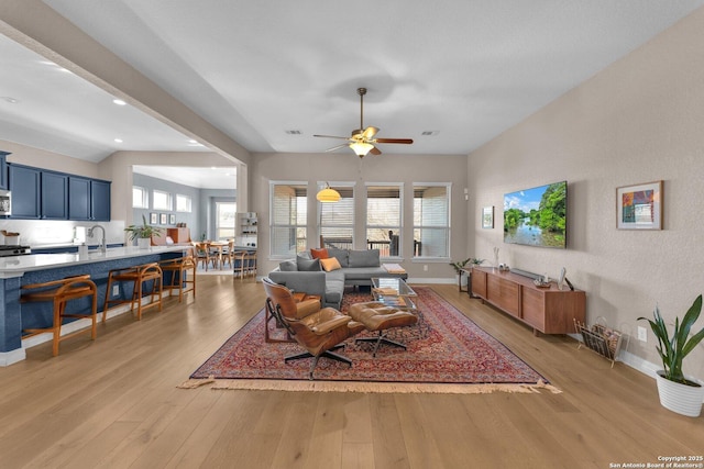 living room with sink, a wealth of natural light, ceiling fan, and light wood-type flooring