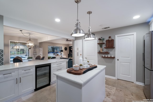 kitchen featuring pendant lighting, beverage cooler, a center island, and white cabinets