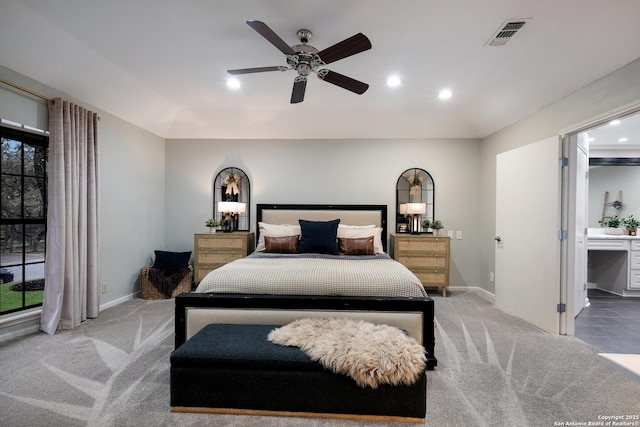 carpeted bedroom featuring multiple windows, ceiling fan, and ensuite bathroom