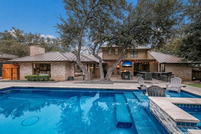 view of pool with a patio area, a hot tub, a bar, grilling area, and exterior kitchen