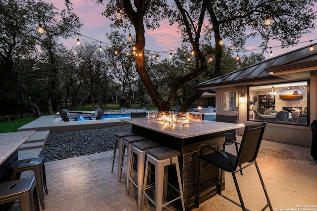 patio terrace at dusk featuring a bar