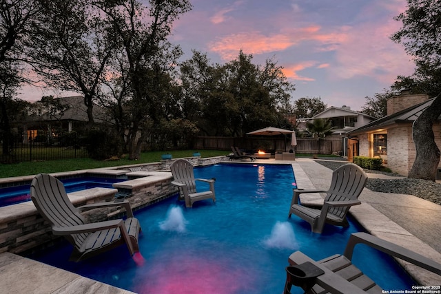 pool at dusk with an in ground hot tub, a patio, and an outdoor fire pit