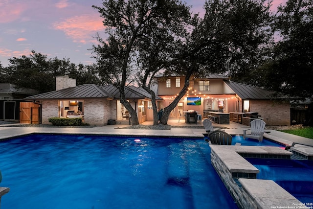 pool at dusk featuring a patio area