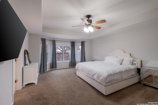 carpeted bedroom featuring a tray ceiling and ceiling fan