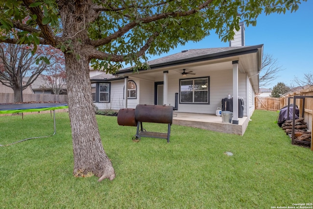 rear view of house with a trampoline, a yard, and a patio area