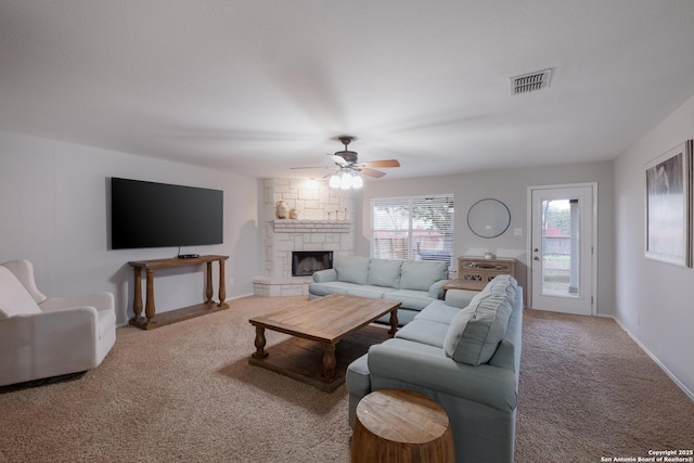 carpeted living room with a fireplace and ceiling fan