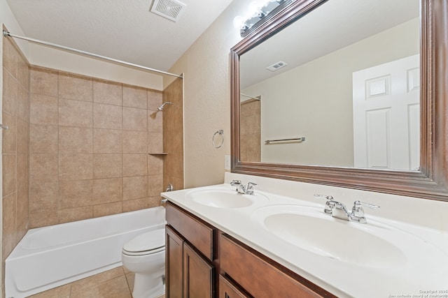 full bathroom with tile patterned floors, toilet, a textured ceiling, vanity, and tiled shower / bath combo