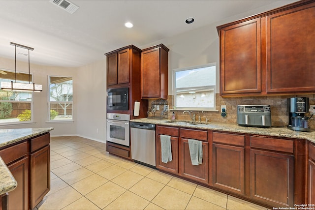 kitchen with stainless steel appliances, hanging light fixtures, sink, and light stone counters