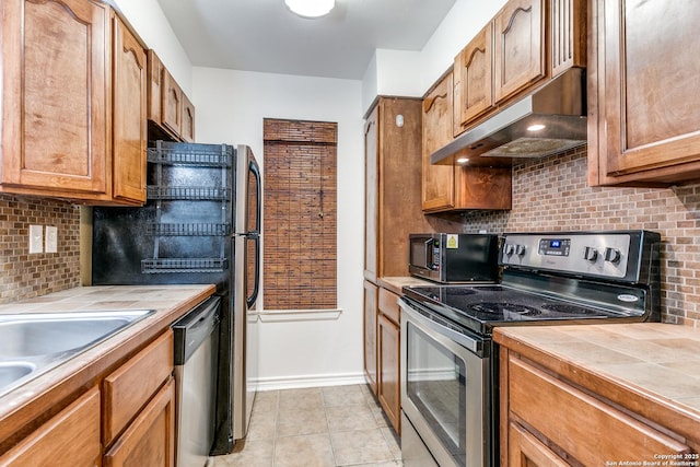 kitchen featuring light tile patterned flooring, stainless steel appliances, tile counters, and backsplash