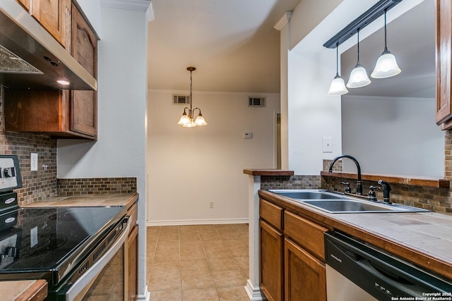 kitchen with sink, tile counters, stainless steel appliances, and hanging light fixtures