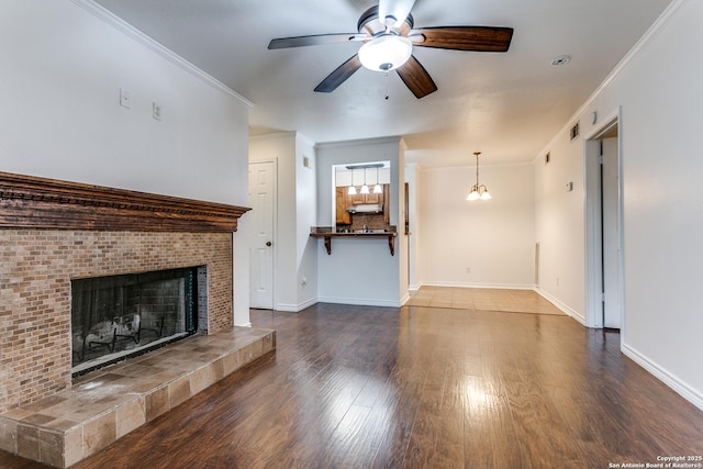 unfurnished living room with hardwood / wood-style floors, crown molding, a tile fireplace, and ceiling fan