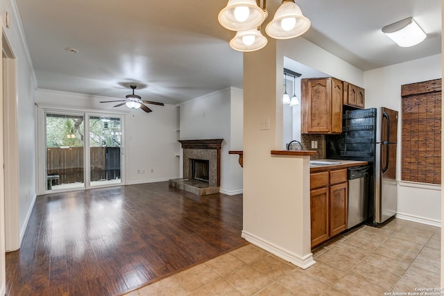 kitchen with stainless steel dishwasher, decorative light fixtures, a tiled fireplace, and backsplash