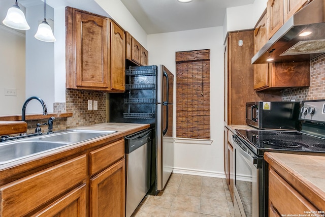 kitchen with sink, light tile patterned floors, stainless steel appliances, decorative backsplash, and decorative light fixtures