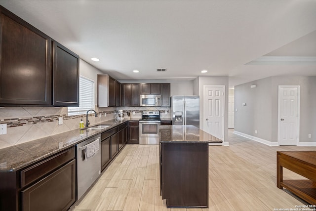 kitchen with dark brown cabinetry, sink, a center island, appliances with stainless steel finishes, and backsplash