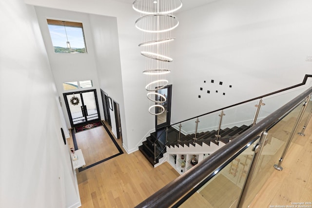 foyer with a notable chandelier, hardwood / wood-style flooring, and a towering ceiling