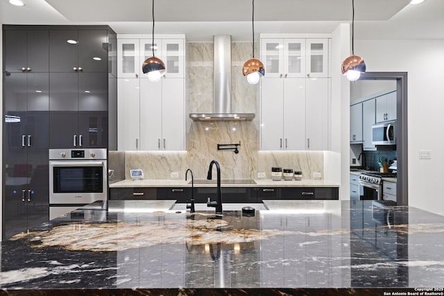 kitchen with white cabinetry, stainless steel appliances, and dark stone counters