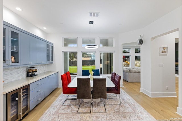 dining space with wine cooler and light wood-type flooring