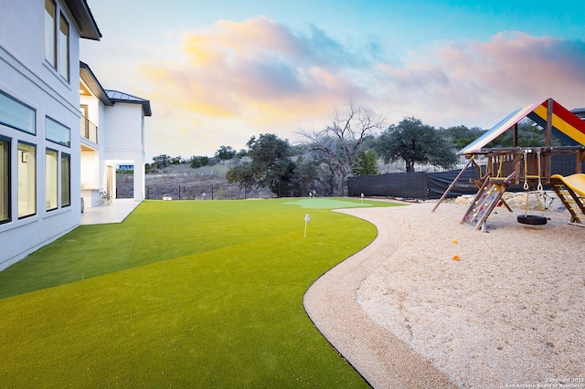 yard at dusk featuring a playground