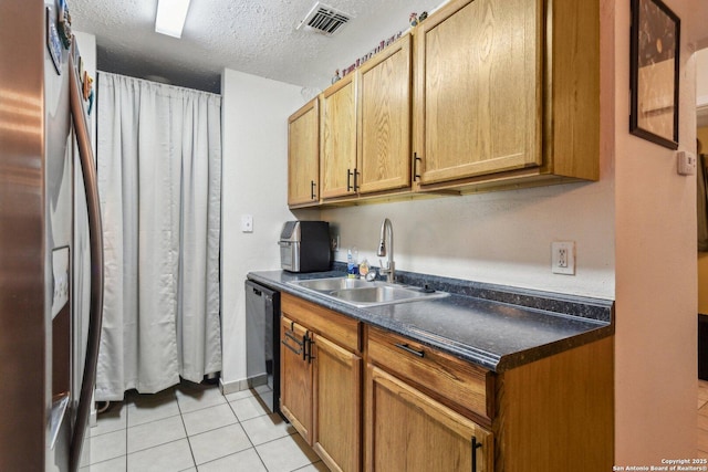 kitchen featuring visible vents, a sink, dark countertops, stainless steel fridge, and light tile patterned floors