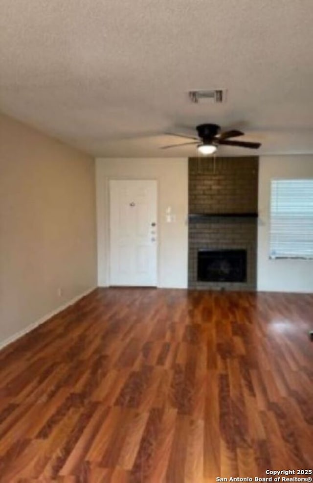 unfurnished living room featuring hardwood / wood-style floors, a fireplace, a textured ceiling, and ceiling fan