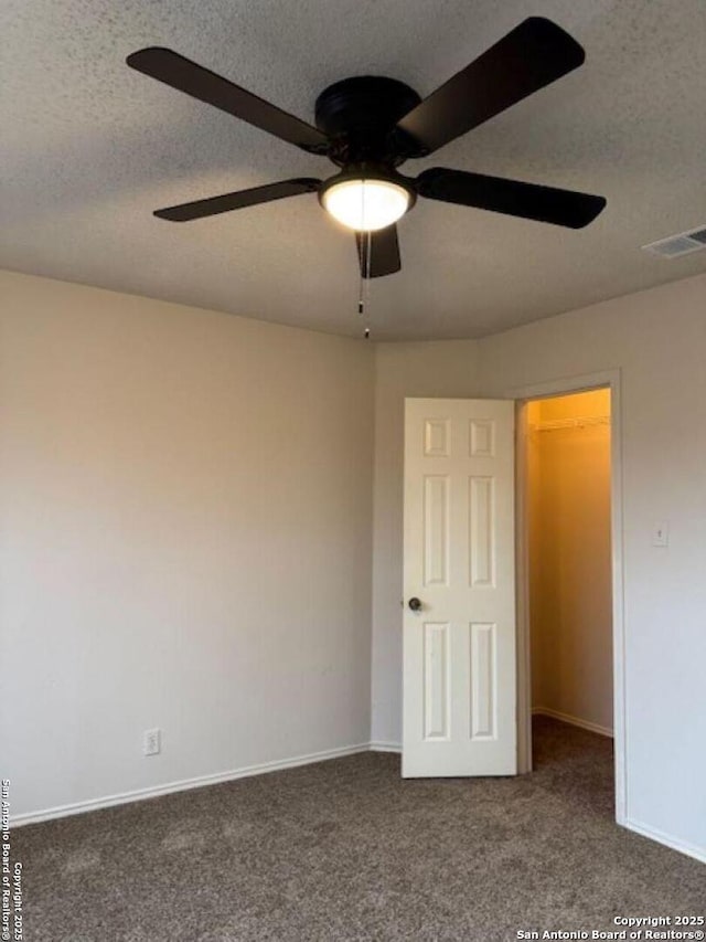 unfurnished bedroom with dark colored carpet, ceiling fan, and a textured ceiling