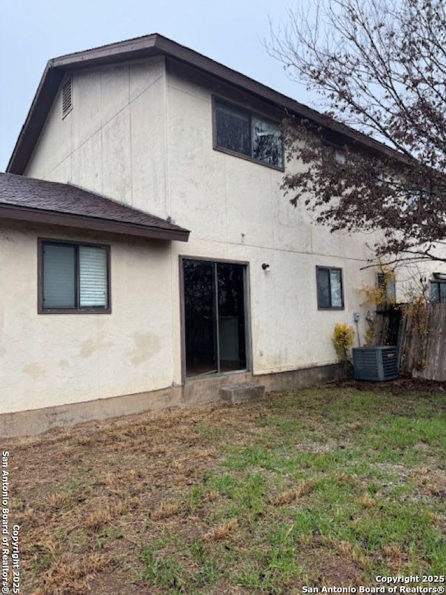 back of property featuring central AC and a yard