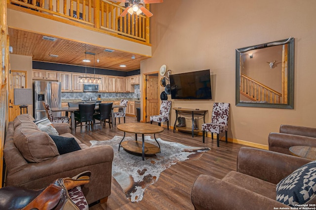 living room with a towering ceiling, wooden ceiling, dark hardwood / wood-style floors, and ceiling fan