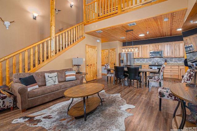 living room featuring dark wood-type flooring, wood ceiling, and a towering ceiling