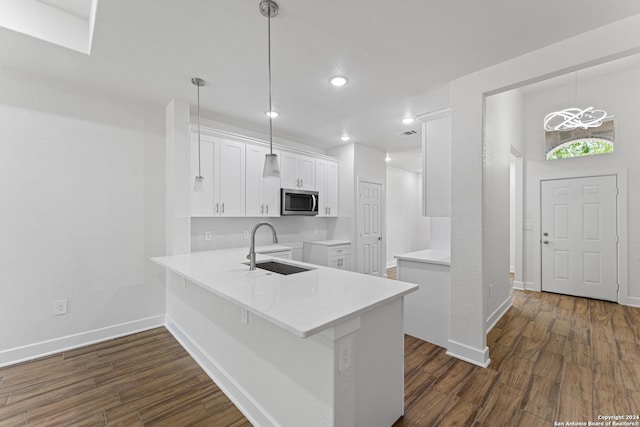 kitchen with sink, white cabinets, dark hardwood / wood-style flooring, hanging light fixtures, and kitchen peninsula