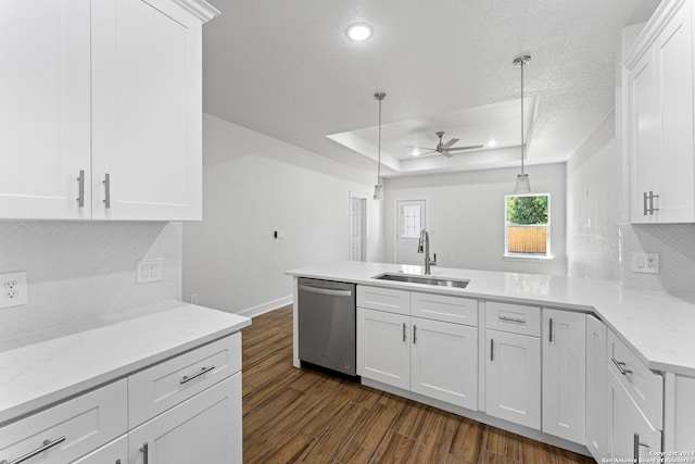 kitchen with sink, decorative light fixtures, stainless steel dishwasher, a tray ceiling, and white cabinets