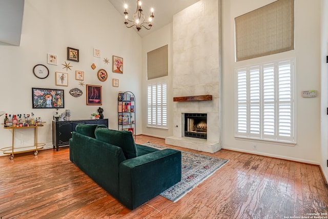 living room with wood-type flooring, a fireplace, a chandelier, and high vaulted ceiling