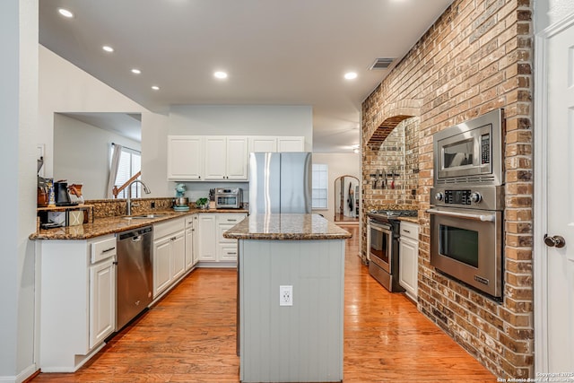 kitchen featuring stone countertops, white cabinetry, sink, a center island, and stainless steel appliances