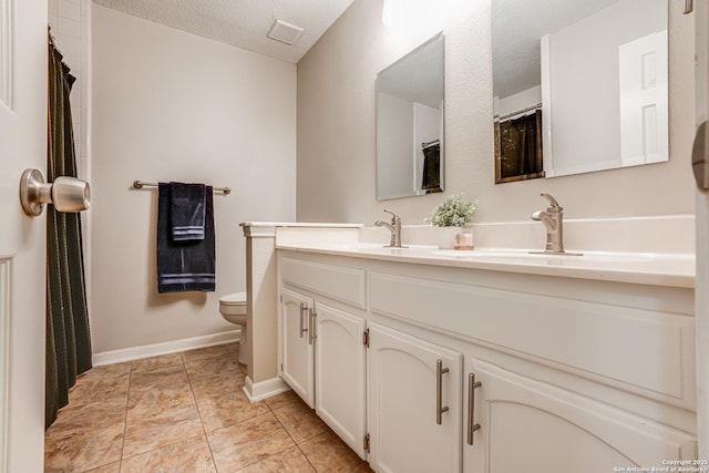 bathroom with tile patterned floors, vanity, toilet, and a textured ceiling