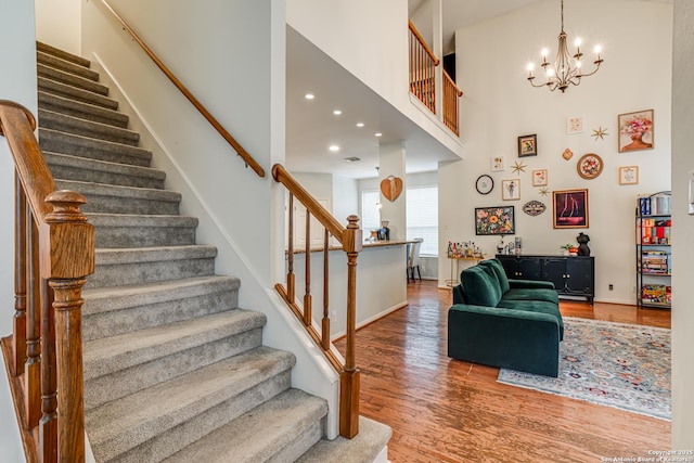 stairs with hardwood / wood-style flooring, a high ceiling, and a chandelier