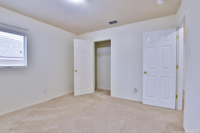 unfurnished bedroom with light carpet, a textured ceiling, and a closet