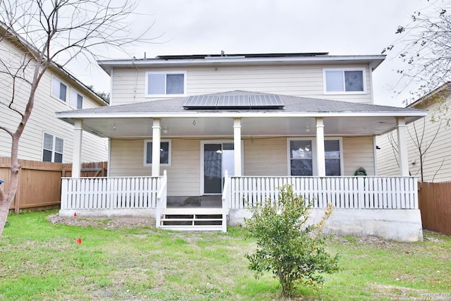 back of property with a lawn, covered porch, and solar panels