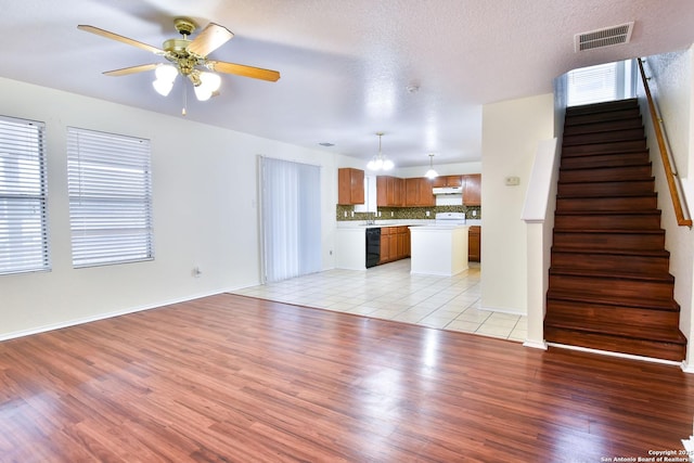 unfurnished living room with ceiling fan, light hardwood / wood-style floors, and a textured ceiling