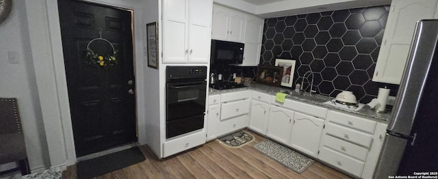 kitchen with dark wood-type flooring, tasteful backsplash, black appliances, white cabinets, and stone countertops