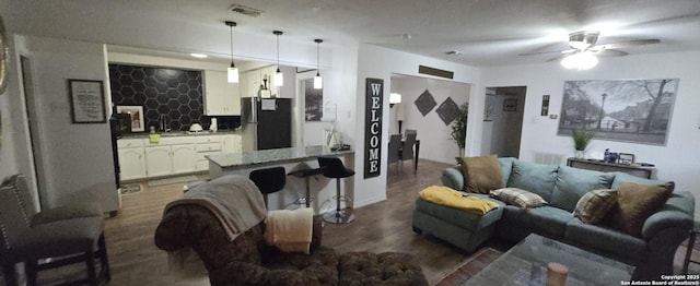 living room featuring wood-type flooring, bar area, and ceiling fan