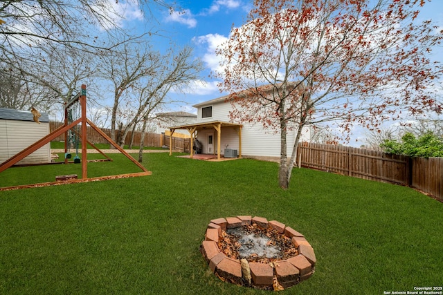 view of yard featuring a playground, central air condition unit, and an outdoor fire pit