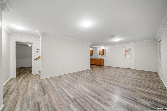 unfurnished living room featuring ornamental molding and light wood-type flooring